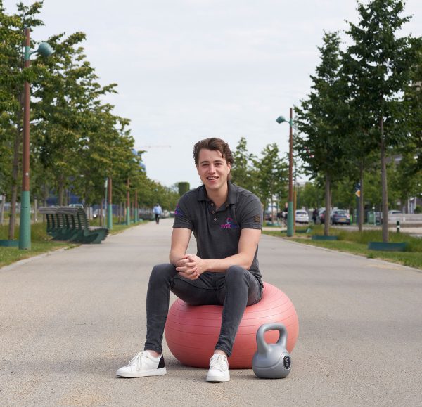 Fysiotherapeut Luc Stassen zit op een rode oefenbal met een kettlebel naast hem in Maastricht.