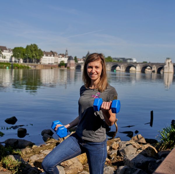 vrouw met dumbells gewichten staat aan het water in Maastricht