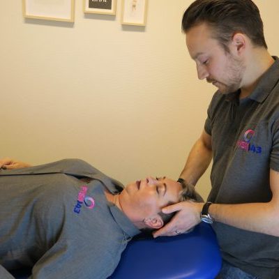 Vrouw ligt op behandeltafel bij fysiotherapeut voor rug- en nekklachten na het slapen en krijgt ontspanningstherapie
