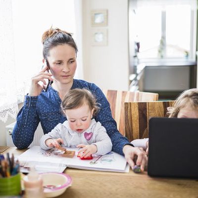 Vrouw met kinderen aan tafel heeft last van spanningshoofdpijn en kijkt naar de klachtenregeling van Fysio043 op haar laptop om een klacht achter te laten