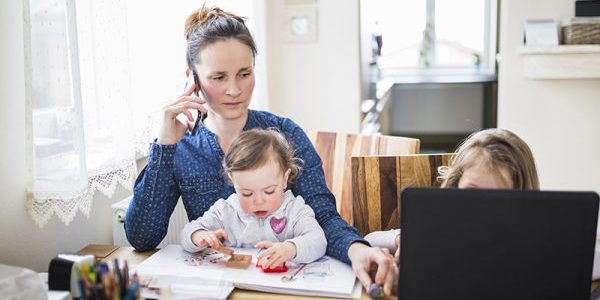 Spanningshoofdpijn Vrouw met kinderen aan tafel heeft last van spanningshoofdpijn en kijkt naar de klachtenregeling van Fysio043 op haar laptop om een klacht achter te laten