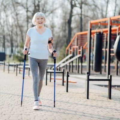 Vrouw loopt door een speeltuin en doet aan revalidatie na een operatie