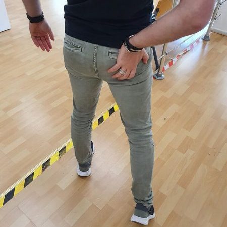 Man heeft last van spit en loopt moeilijk vooruit door zijn hand op zijn rechter achter rug te plaatsen
