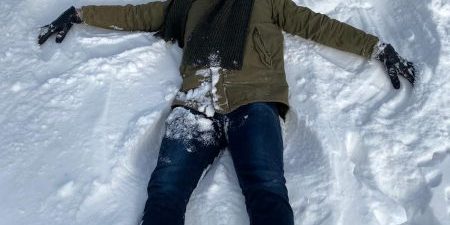 Blessures wintersport Man maakt engeltje in de sneeuw, hij voorkomt blessures bij wintersport