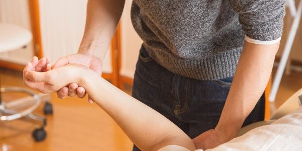 Schouderklachten Persoon ligt bij de fysio om naar zijn schouderklachten te lat en kijken