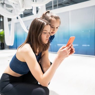Meisje neemt een incorrecte houding aan en laat wat op haar telefoon zien aan een ander meisje en zegt bedankt voor de fysiotherapie behandeling