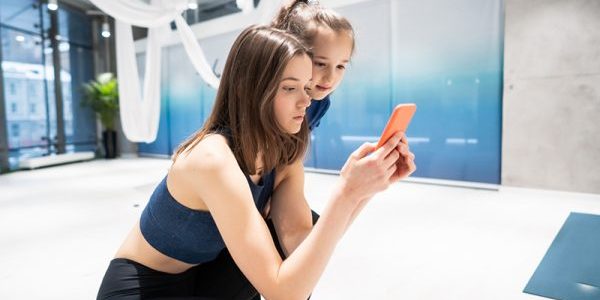 Houding Meisje neemt een incorrecte houding aan en laat wat op haar telefoon zien aan een ander meisje en zegt bedankt voor de fysiotherapie behandeling