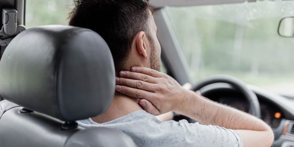 nekpijn tijdens het autorijden Man heeft last van nekklachten in Bunde tijdens het autorijden en voelt aan zijn nek in de auto.